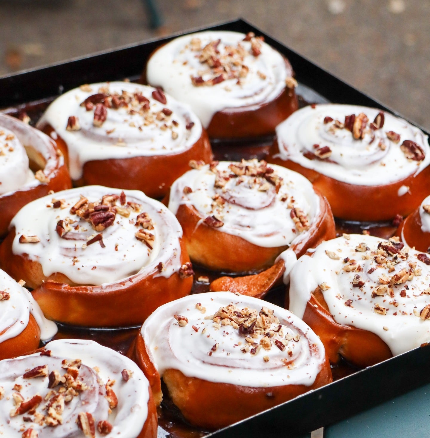 Baked goods with white icing and pecans on a tray