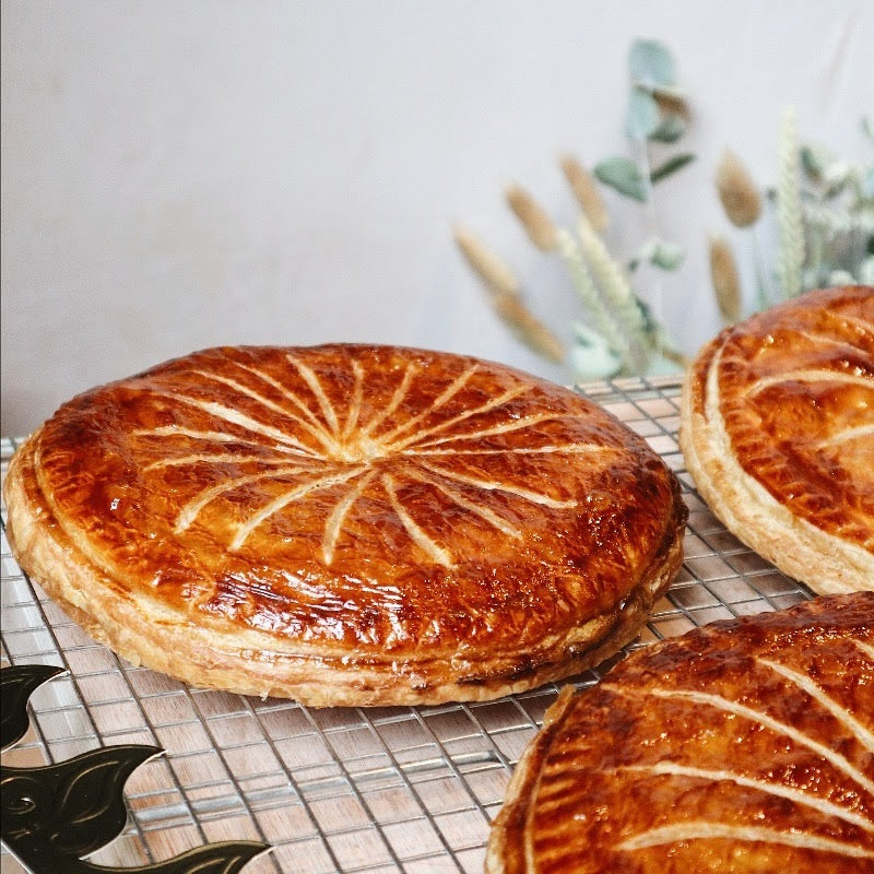 Three round baked pastries with decorative crust on a cooling rack.