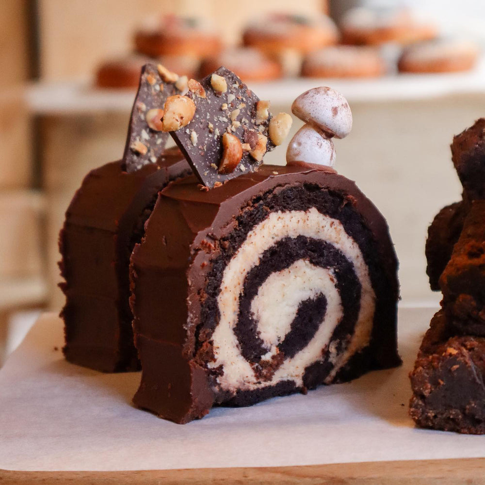 
                      
                        Chocolate yule log with a white cream filling on a wooden board.
                      
                    