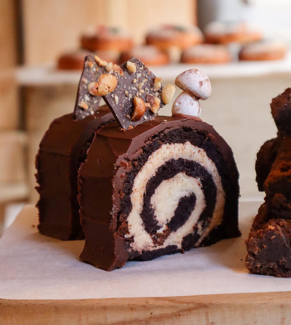 Chocolate yule log with a white cream filling on a wooden board.